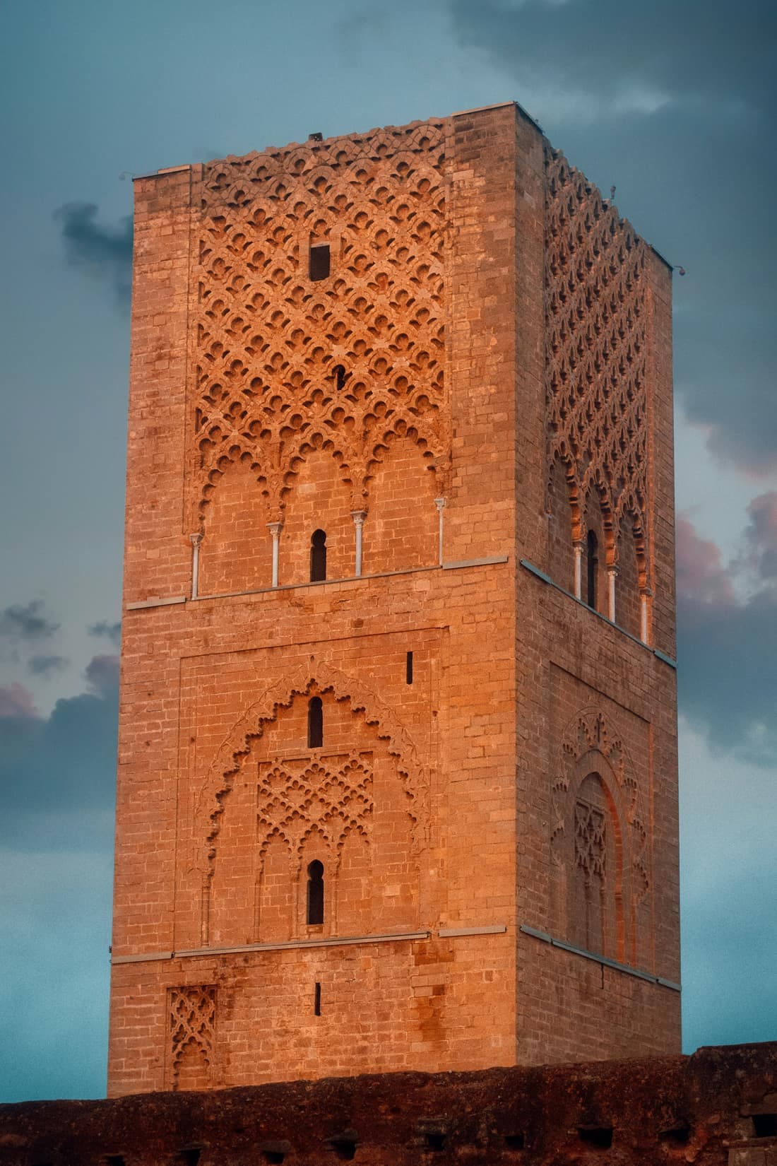 Close view of the carved sandstone face of the Hassan Tower in Rabat, with its interlaced arch patterns.
