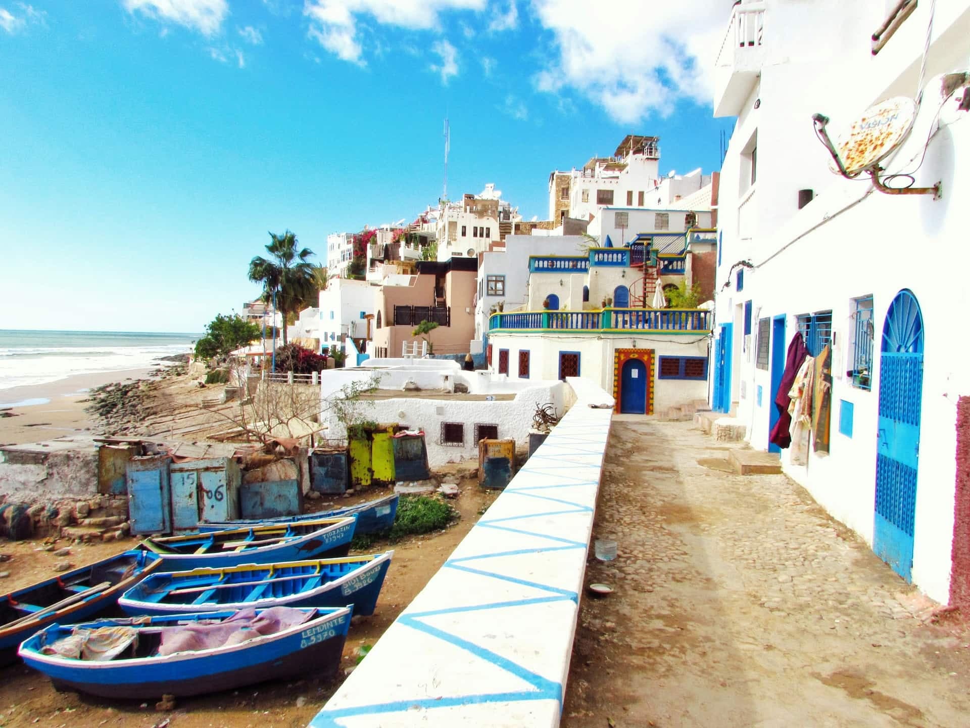 Whitewashed houses and blue fishing boats above the beach at Taghazout, the surf village north of Agadir.