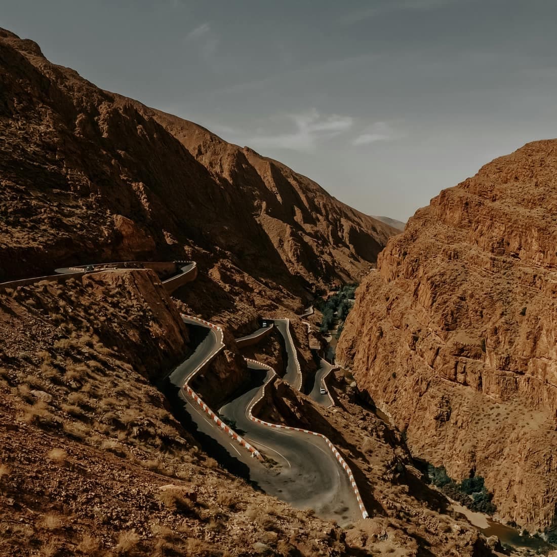 The hairpin road of the Dades Gorges near Boumalne Dades, winding up a narrow canyon in low evening light.