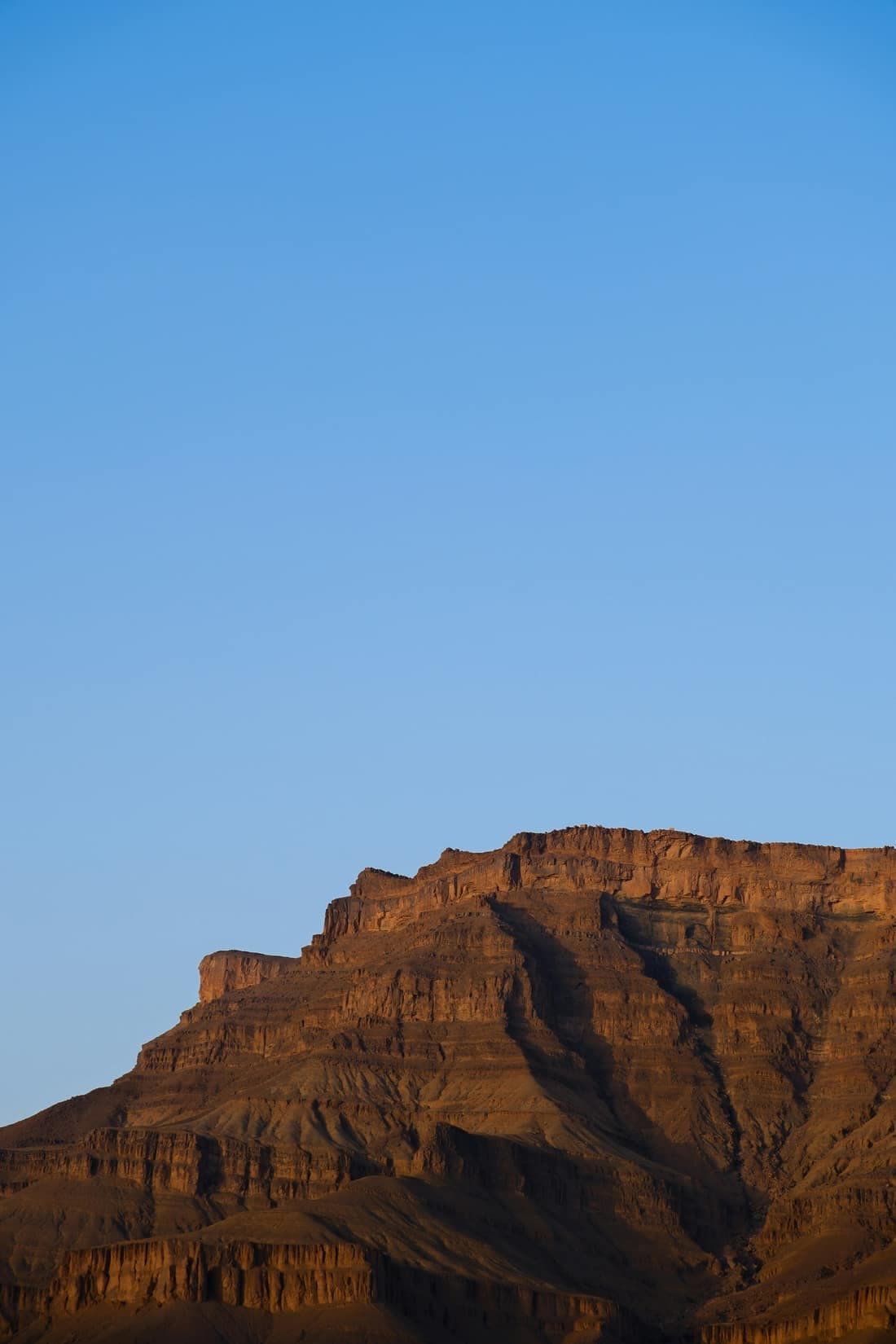 A flat-topped rocky ridge near Zagora catching the sun against a wide, clear blue sky.