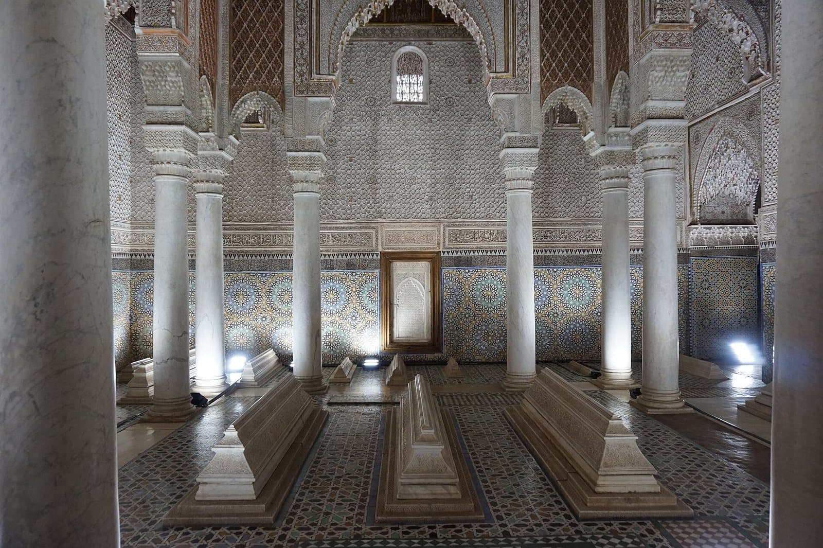 The Hall of Twelve Columns in the Saadian Tombs, with marble tombs on a zellige floor beneath carved stucco arches and a gilded ceiling.